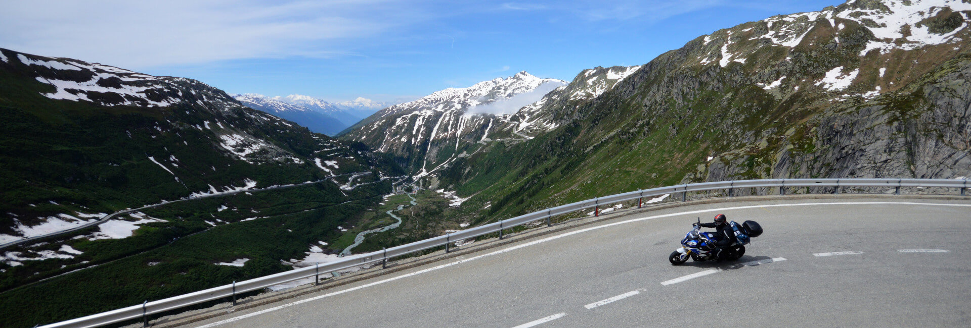 Motorcyclist riding with alps in the distance.